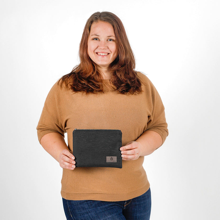 Woman holding a black zip pouch against a white background named after Harmony