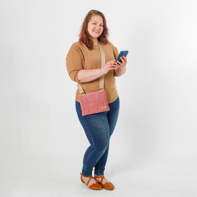 Woman holding a phone with a pink crossbody bag on a white background named after Holly 