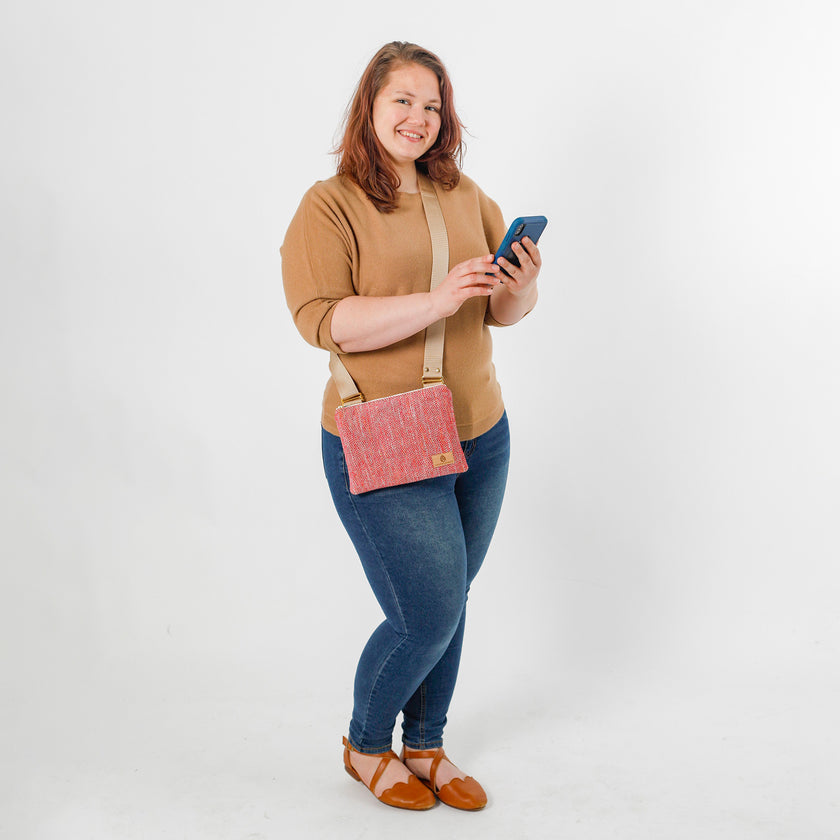 Woman holding a phone with a pink crossbody bag on a white background named after Holly 