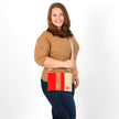 Woman holding a red and beige crossbody bag against a white background named after Honey 