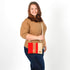 Woman holding a red and beige crossbody bag against a white background named after Honey 