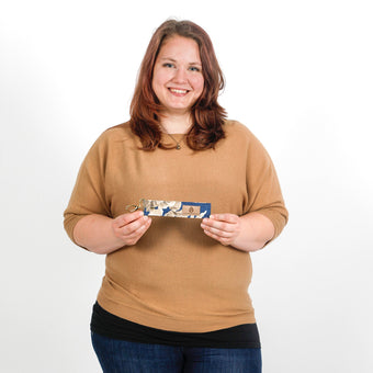 Woman holding a blue flower key clip  named Hope against a white background