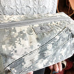 Close up of a gray suede label on a toiletry kit handcrafted from upcycled  US army uniforms. 