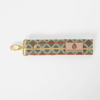 Fabric key clip with a green, yellow and orange pattern and 'Unshattered' branding named Imelda on a white background