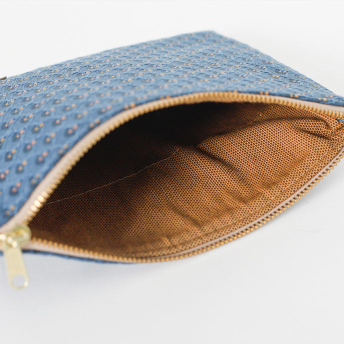 Blue pouch with gold zipper and light brown interior on a white background