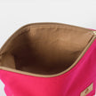 Open hot pink makeup bag with beige interior on a white background
