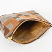 Pinstripe fabric interior of a zippered pouch with a modern geometric square pattern in various shades of brown on a white table
