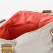 A coral interior fabric with a gold seam on a outdoor furniture material exterior with brown straps and gold hardware 