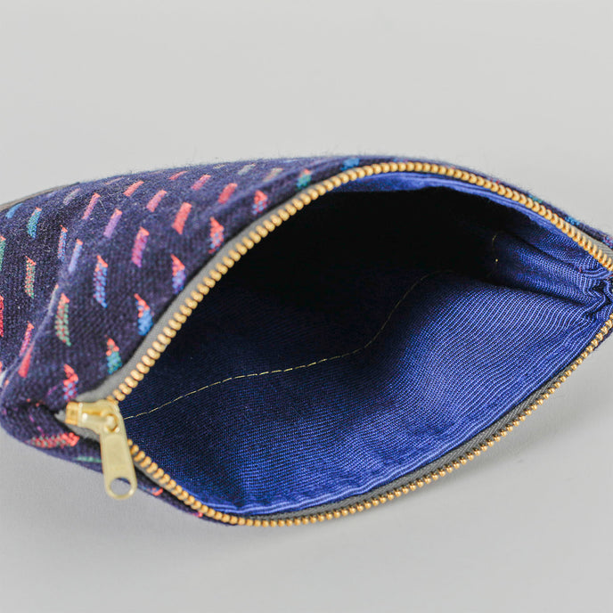 A blue fabric with gold tone hardware on a dark blue zip pouch with multi-color lines named after Keri