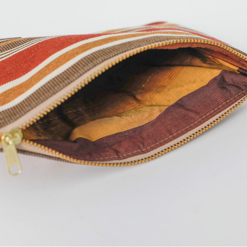 Striped pouch with a gold zipper on a light gray background