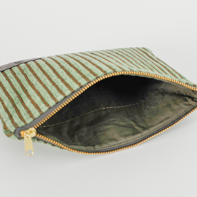 Green fabric interior of a green plush zippered pouch against a gray background
