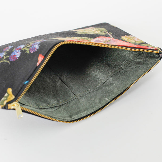 A green fabric interior on a black fruit design large zip pouch named after Diane 