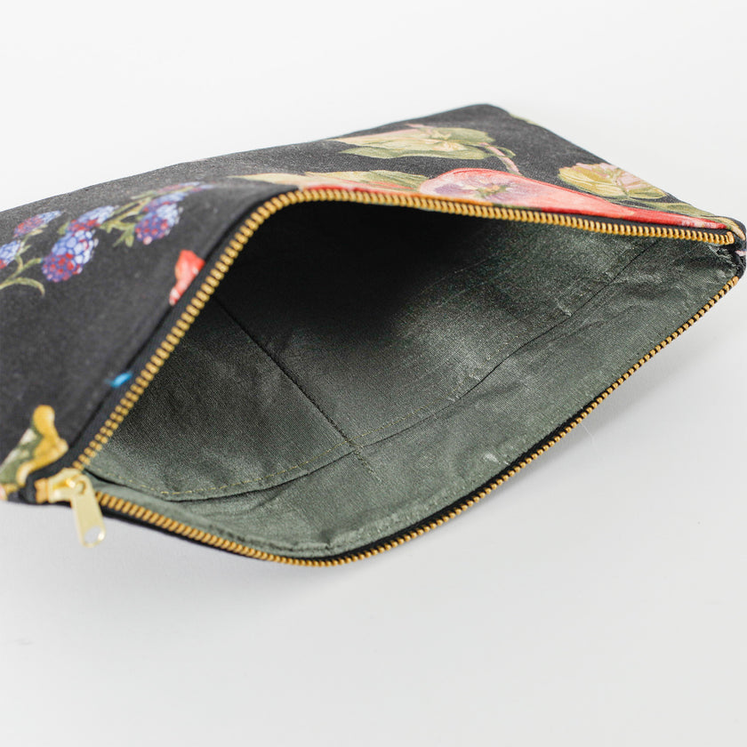 A green fabric interior on a black fruit design large zip pouch named after Diane 