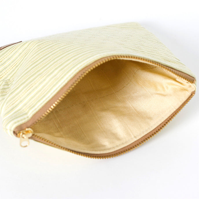 Yellow upcycled fabric interior of a zippered pouch with a gold-tone zipper named after Katya on a white background
