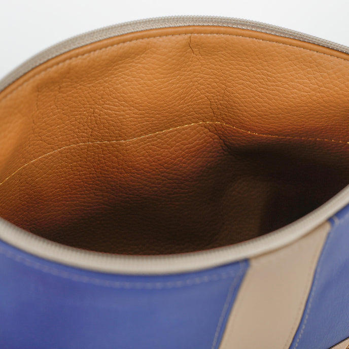 Close-up of a blue and beige leather bag with a brown interior.
