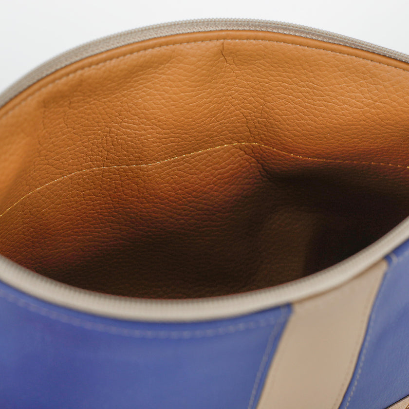 Close-up of a blue and beige leather bag with a brown interior.