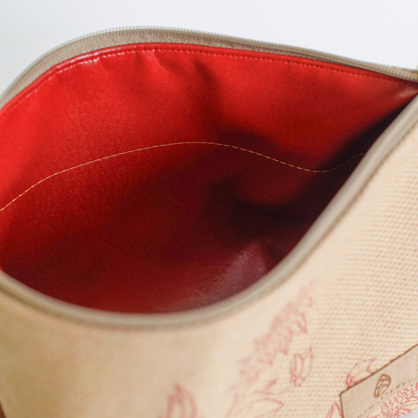 Close-up of a beige makeup kit with red interior and floral patterns on a light gray background