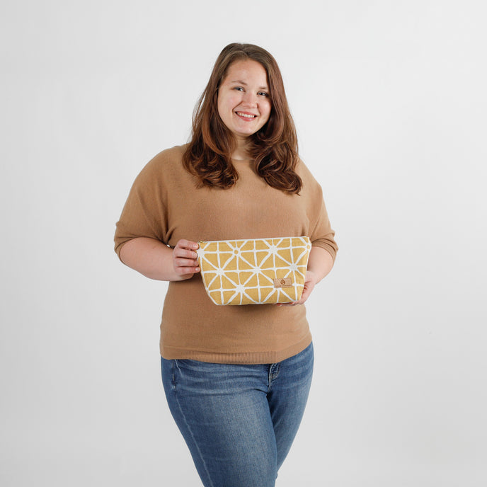 Woman holding a yellow geometric-patterned makeup bag against a white background