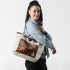 A woman carrying a unlined leather Tote bag with tiger stripe pattern and beige handle on a white background named after Jackie 