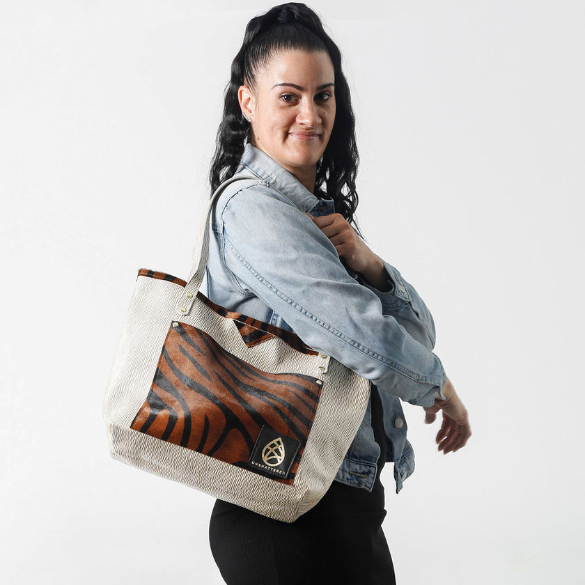A woman carrying a unlined leather Tote bag with tiger stripe pattern and beige handle on a white background named after Jackie 
