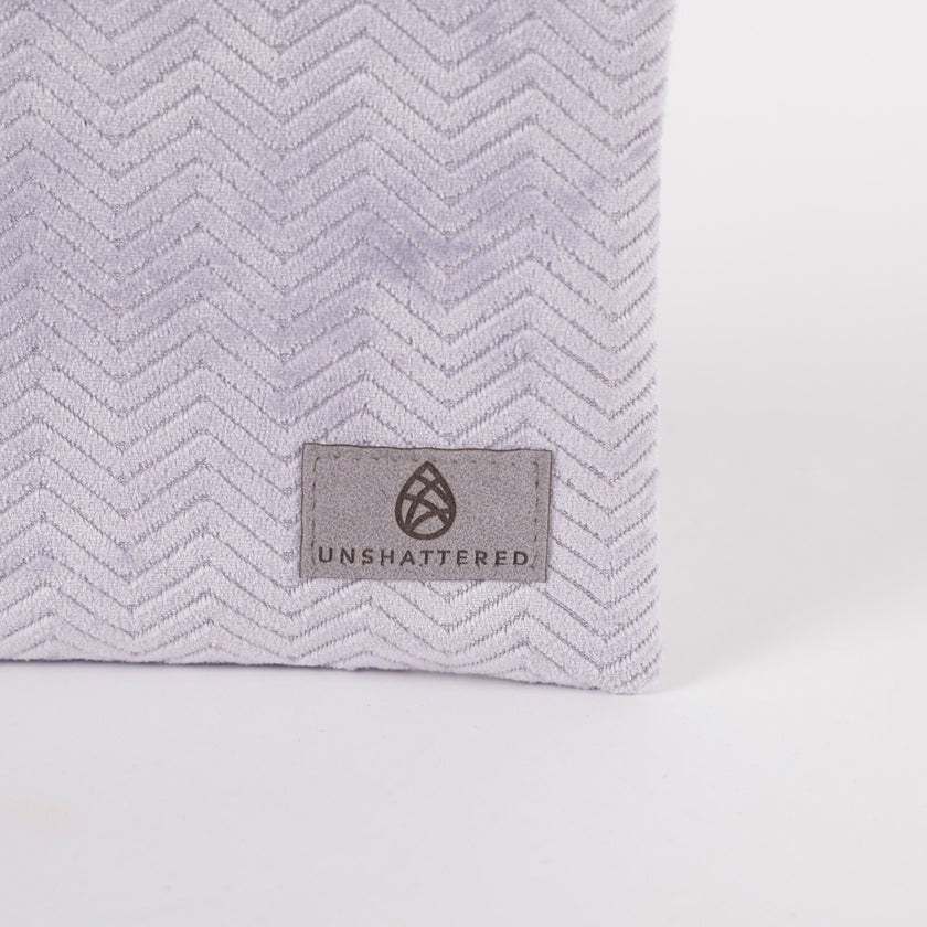Light purple  textured bag with 'Unshattered' brand label on a white background named after Jaimilee