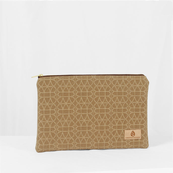 A beige large zip pouch with a geometric pattern and gold-tone hardware, featuring a brand tag with the name Unshattered