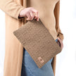 A woman wearing a tan turtleneck and jeans holding a brown geometric design with a tan label
