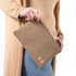 A woman wearing a tan turtleneck and jeans holding a brown geometric design with a tan label