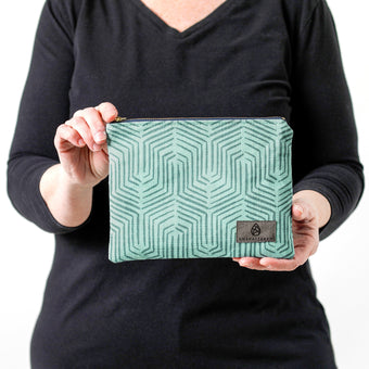 A woman holding a teal colored geometric design zip pouch named after Janet 