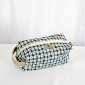 A blue and white plaid toiletry kit with a tan zipper and hardware, displayed against a white background.