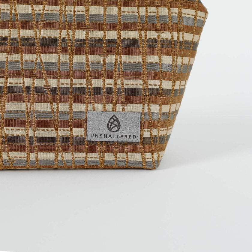 A gray label on a brown and gray makeup kit with gold 