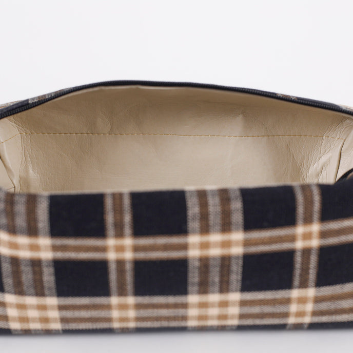 Close-up of a plaid fabric toiletry bag with beige lining on a white background named after Jeremiah 