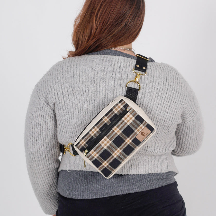 A woman wearing a black/coffee plaid errand bag named after Jesus 
