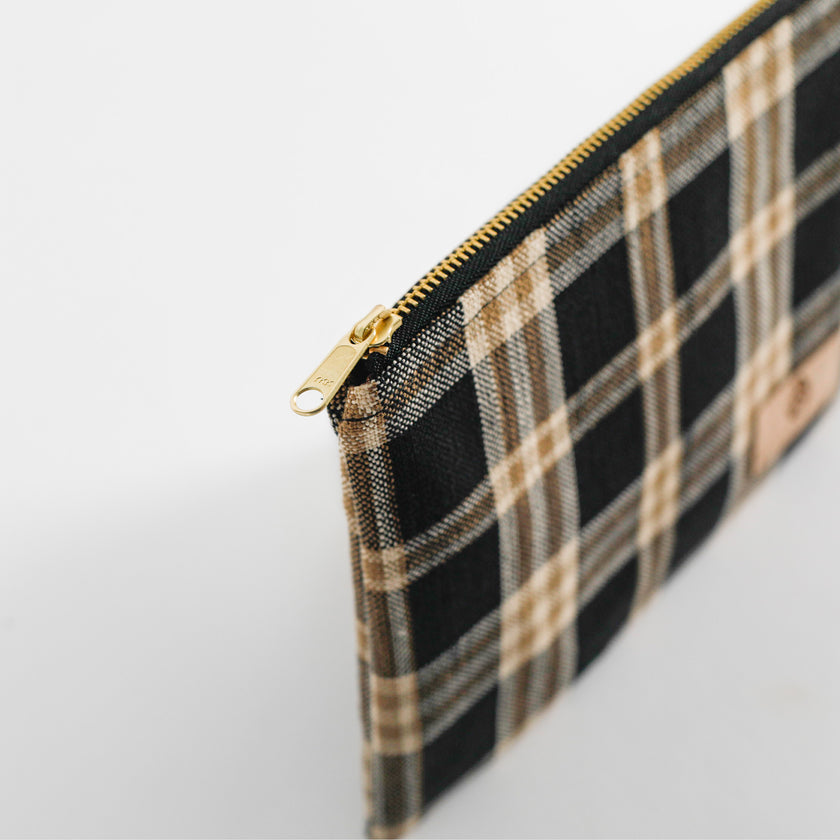 Plaid pouch with gold zipper on a light gray background named after Jeyana
