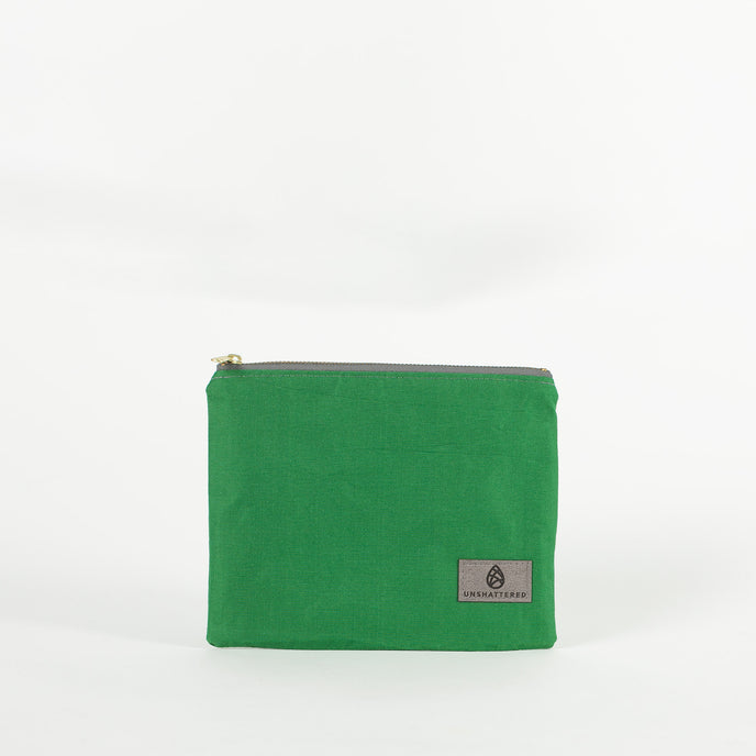 A green zip pouch with a gray Unshattered label on a white background