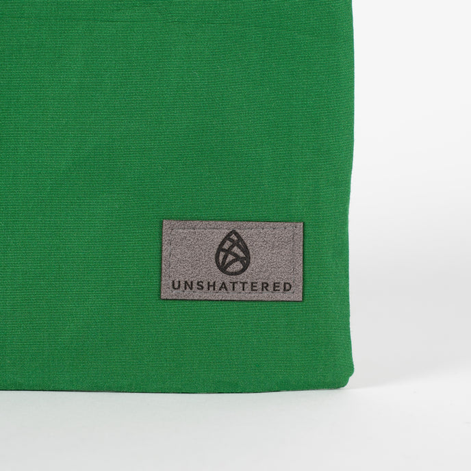 A gray Unshattered label on this green zip pouch 