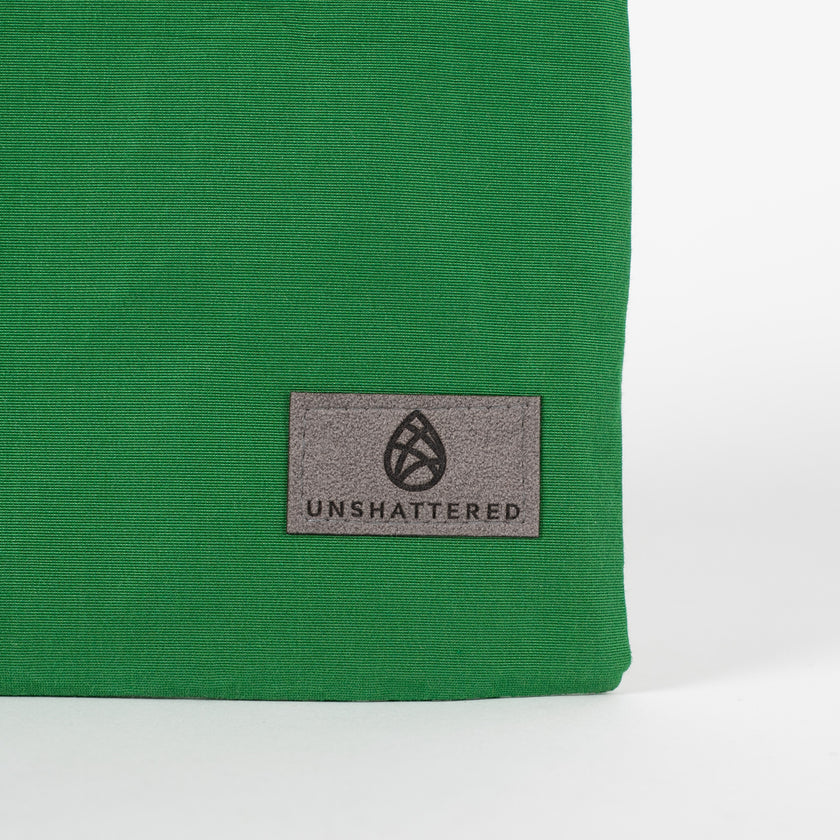A gray Unshattered label on this green zip pouch 