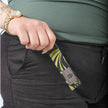 A person holding a black with green design loop keychain with a gray label 