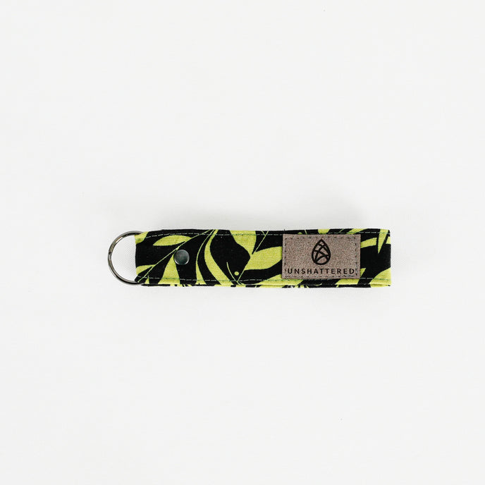 A black fabric with green floral fabric loop keychain with black hardware 