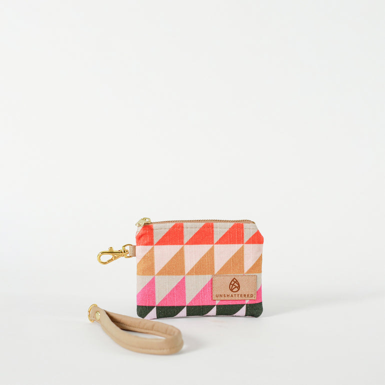A small zippered clip pouch with a geometric pattern of bright triangles and a detachable wristlet strap, displayed against a white background named after Judy.