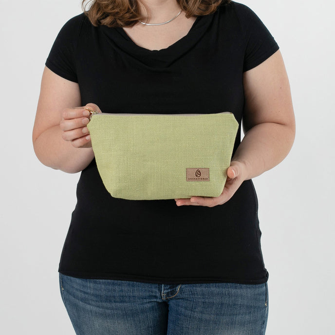 A woman holding a green fabric makeup kit with a tan Unshattered label 