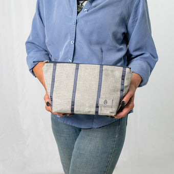 A woman holding a gray and blue striped makeup kit 