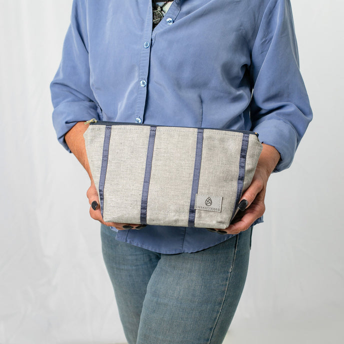 A woman holding a gray and blue striped makeup kit 