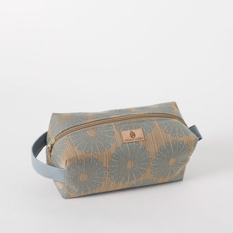 A blue and beige floral toiletry kit with a zipper closure and a Unshattered brand tag on the front.
