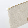 A gold tone zipper on a beige zip pouch 
