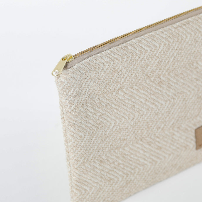 A gold tone zipper on a beige zip pouch 