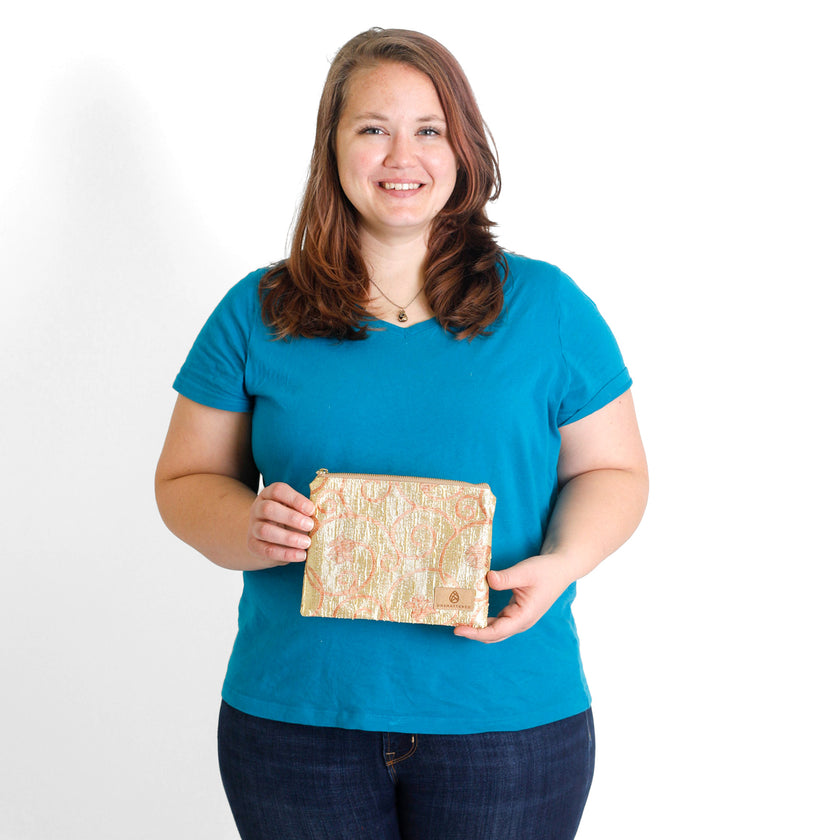 Woman holding a shimmery, gold zippered pouch against a white background