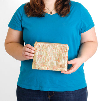 A woman holding a gold and orange design zip pouch named after Katima