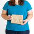 A woman holding a gold and orange design zip pouch named after Katima