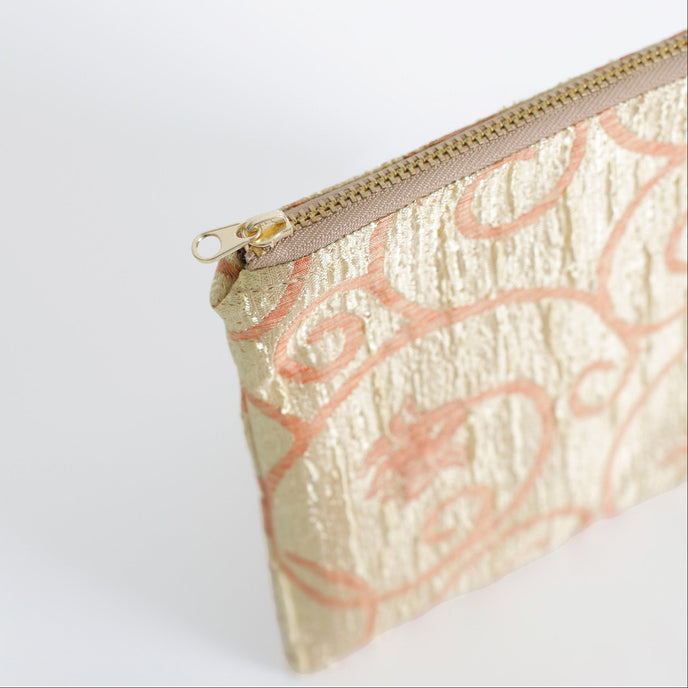 Gold pouch with pink floral pattern on a white background